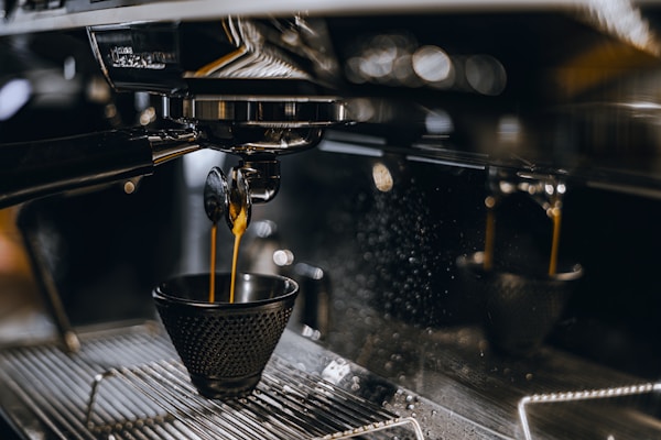 a cup of coffee being poured into a coffee machine