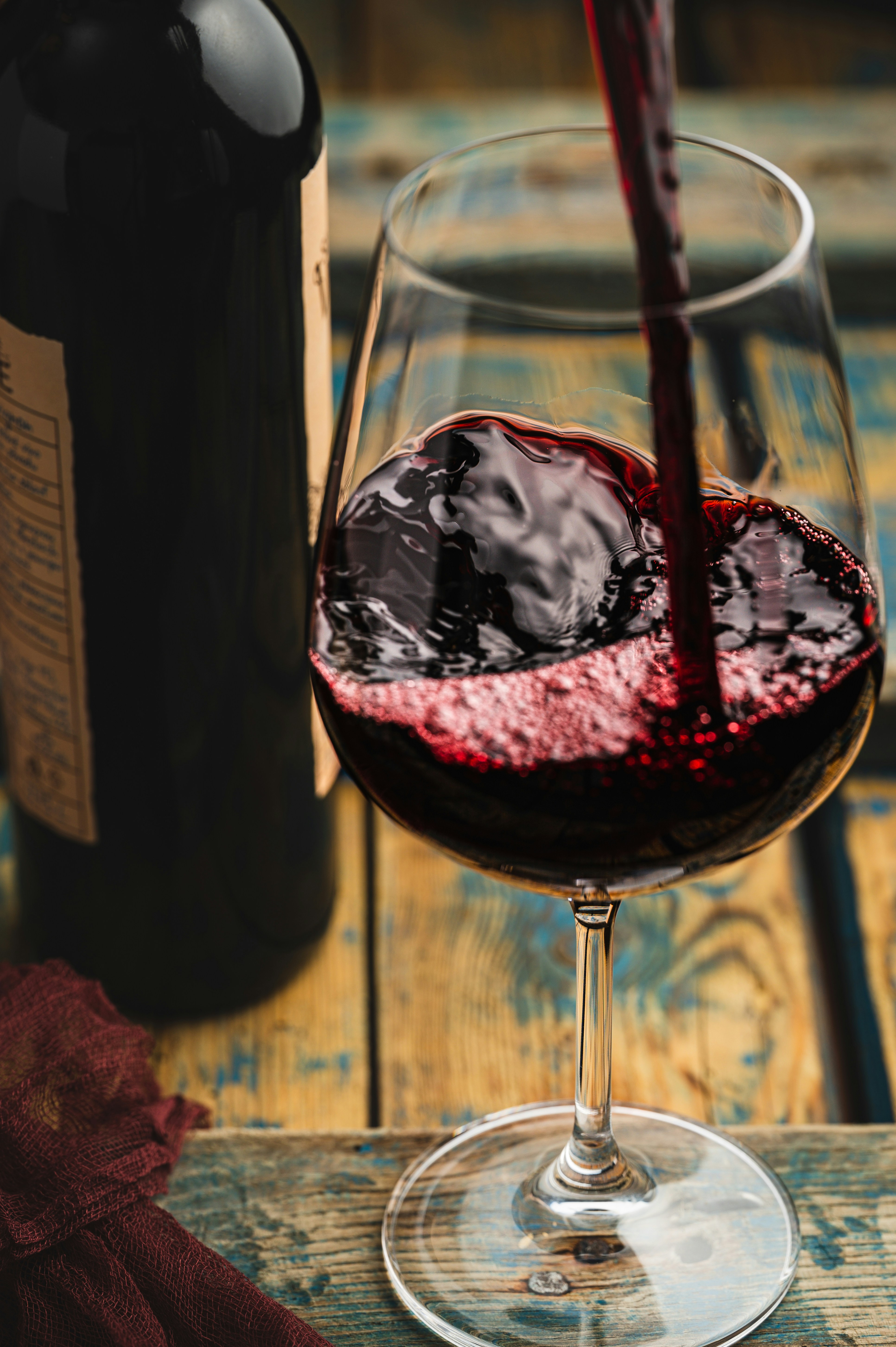 a glass of red wine being poured into a wine glass