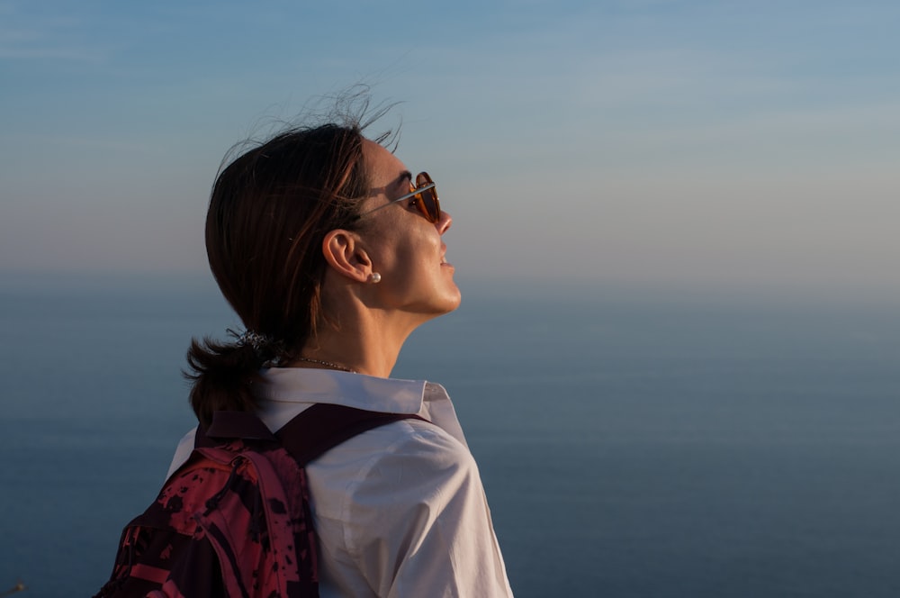 a woman with a backpack looking at the ocean