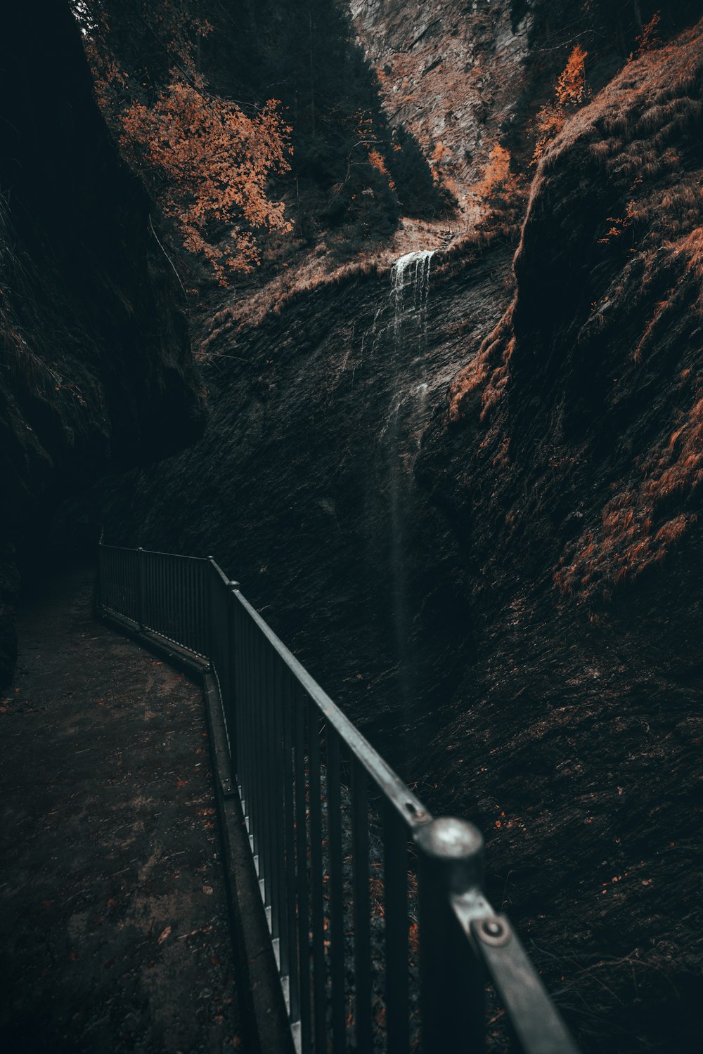 a metal fence next to a mountain with a waterfall