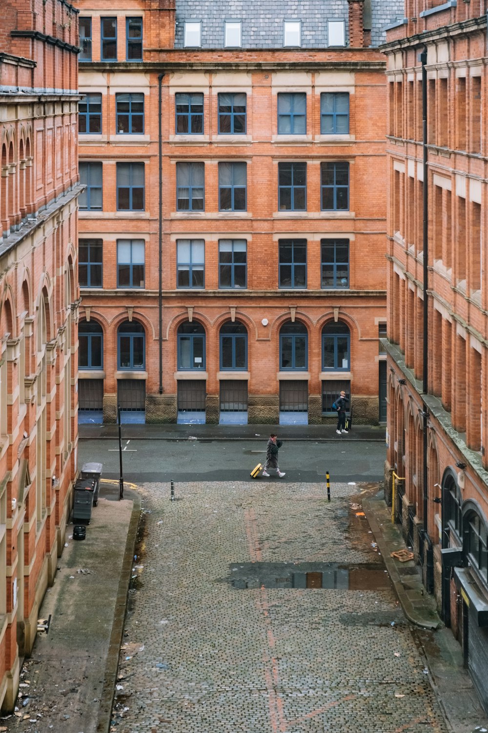 a courtyard in a large brick building with a clock tower in the background