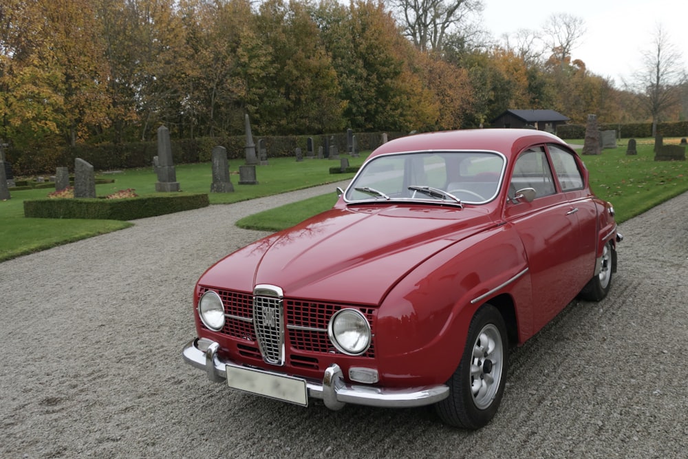 Ein rotes Auto, das auf einer Schotterstraße geparkt ist