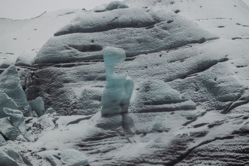 a snow covered mountain with a small snowman on top of it