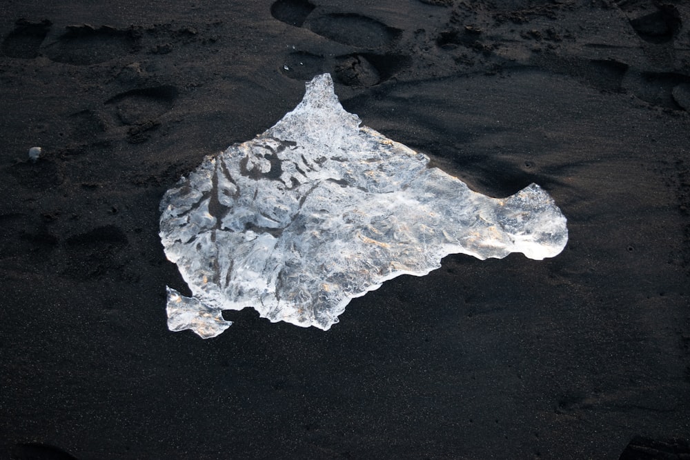 a piece of ice sitting on top of a sandy beach