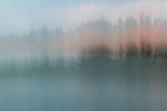 a blurry photo of a body of water with trees in the background