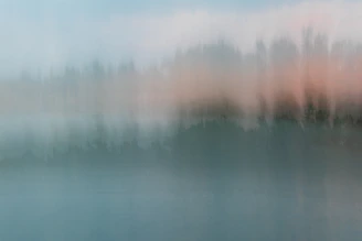a blurry photo of a body of water with trees in the background