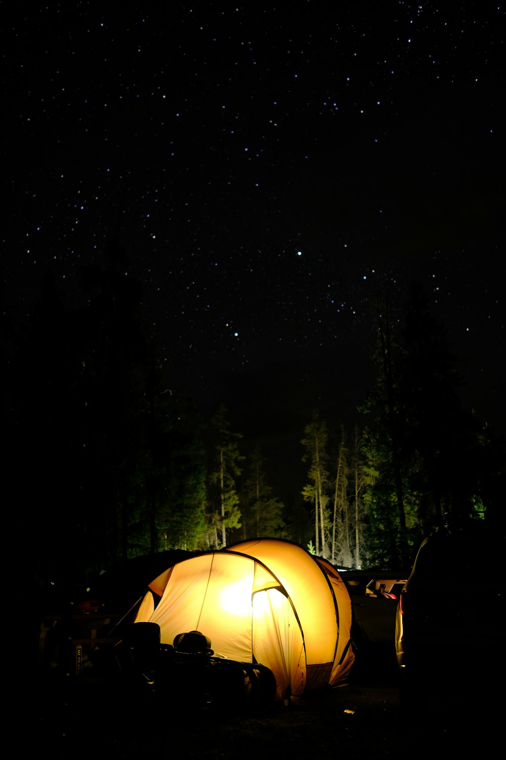 a tent is lit up at night in the woods
