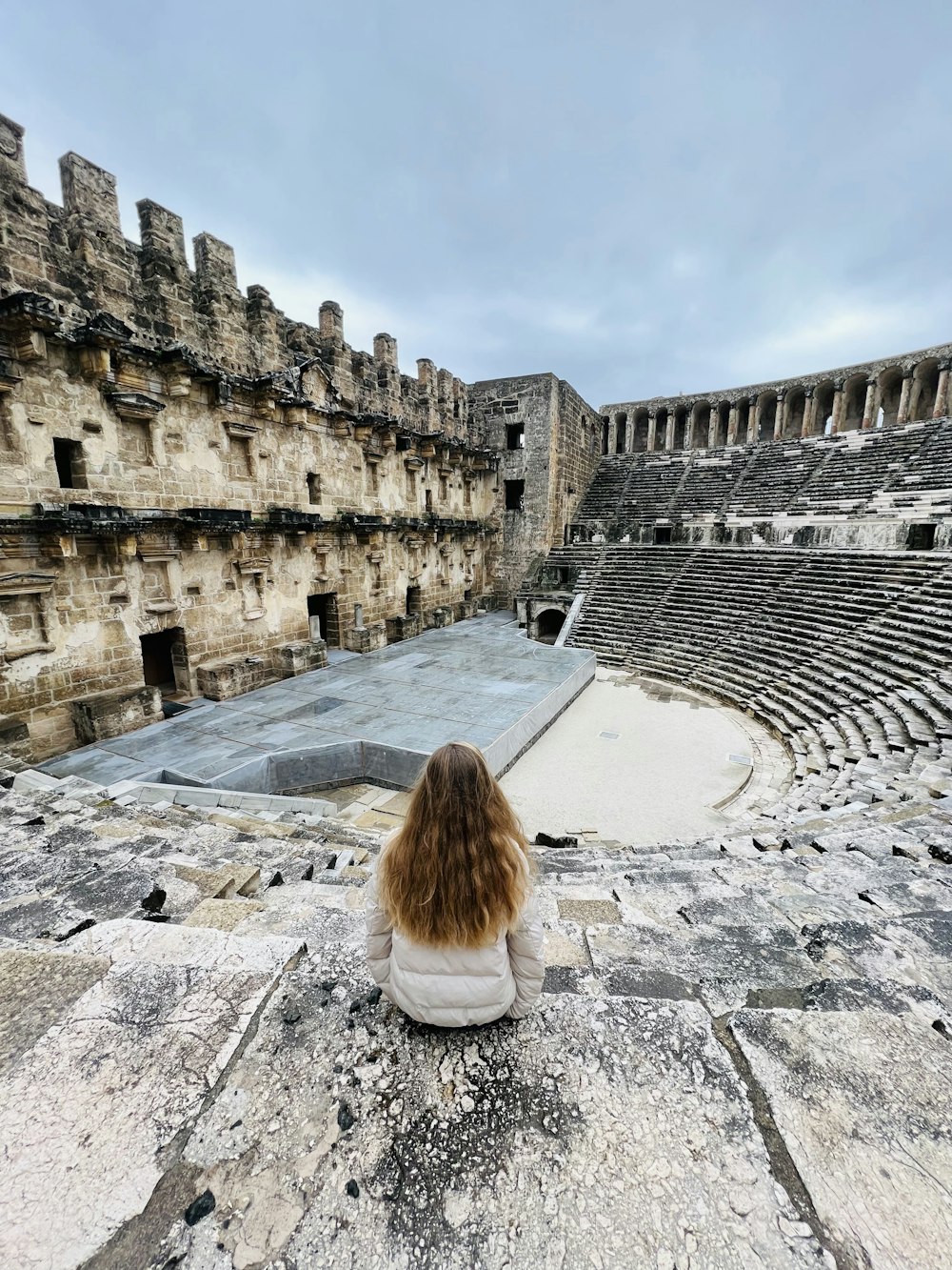 a woman sitting on a ledge looking at an old theater