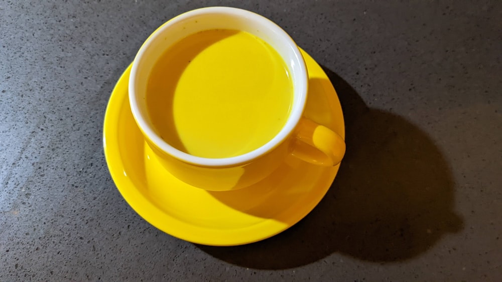a cup of tea sits on a yellow saucer