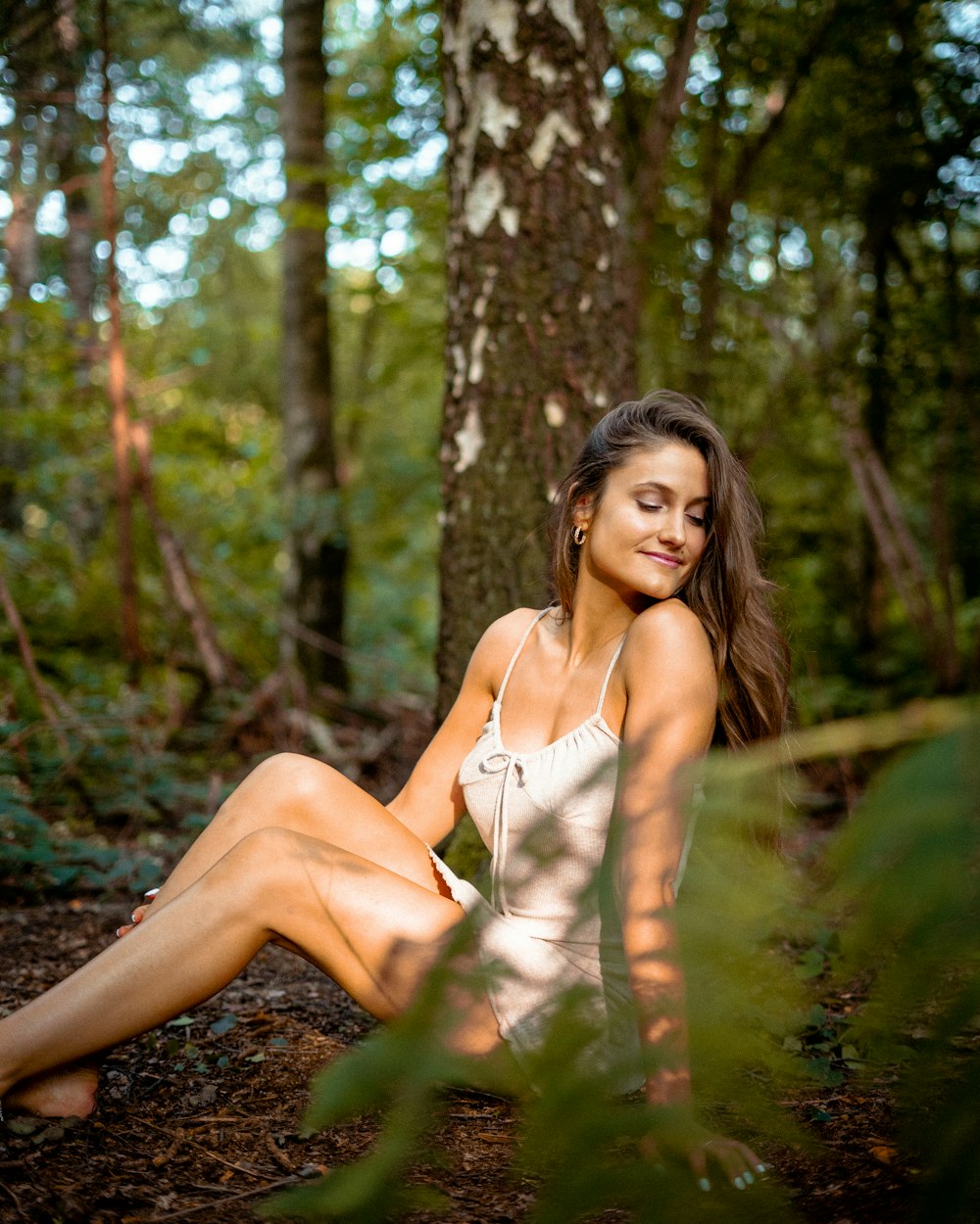 a woman sitting on the ground in the woods