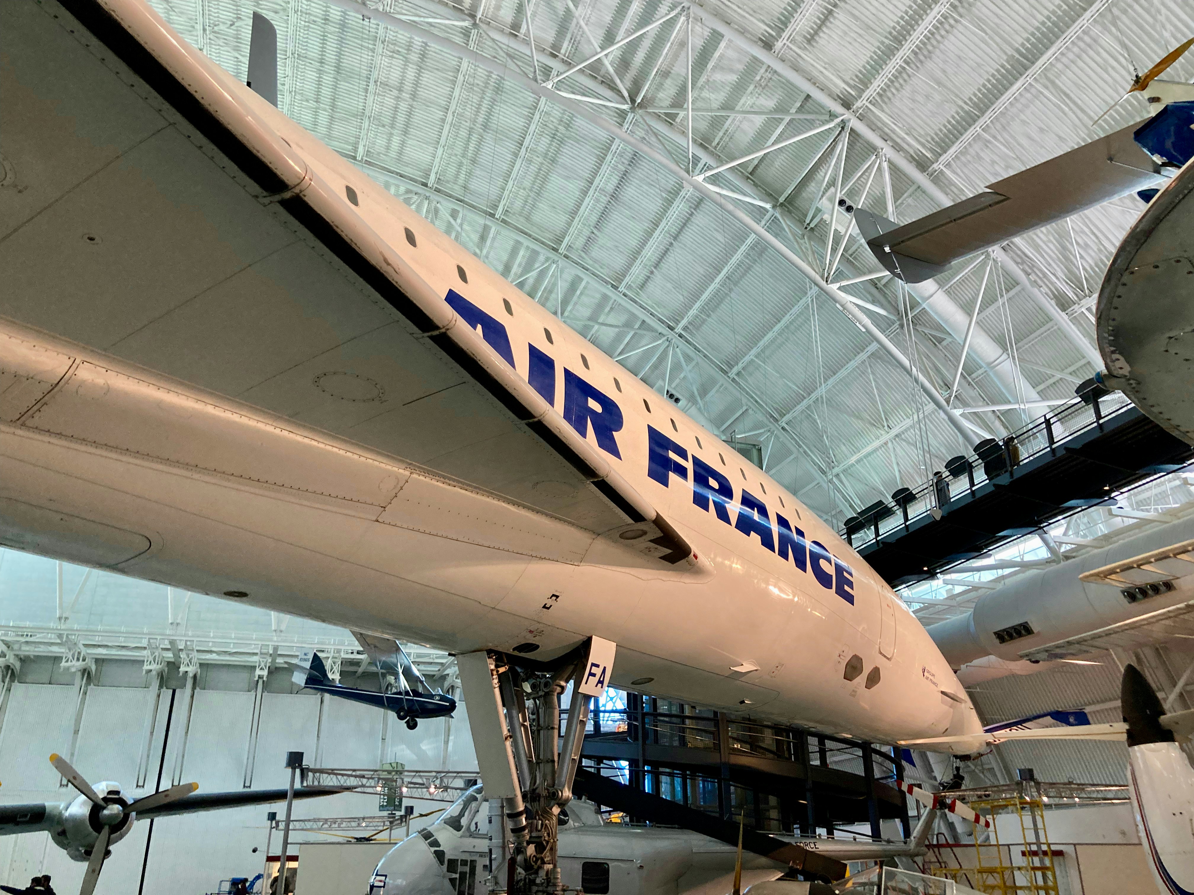 a large white airplane sitting inside of a hangar, Side view of an Air France Concorde in the Air and Space Smithsonian Museum in Virginia