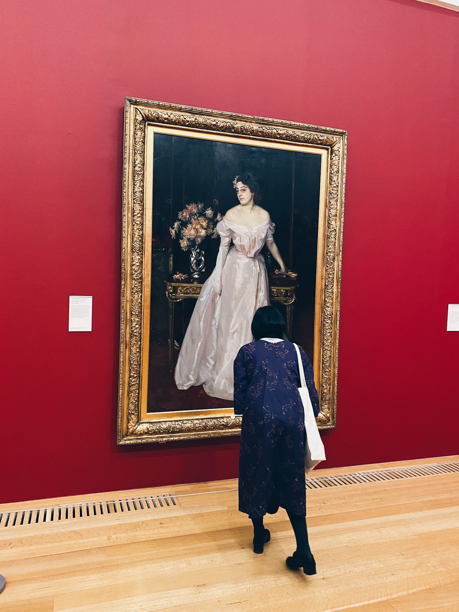 A woman standing close to a painting in a quiet gallery room