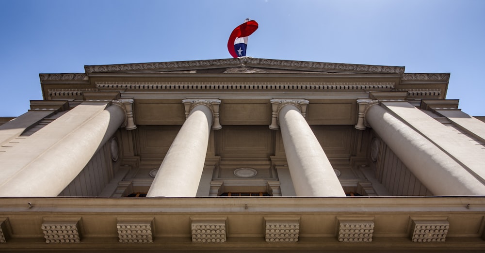 um edifício alto com colunas e uma bandeira no topo