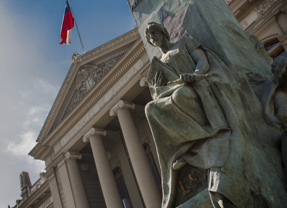 uma estátua de uma mulher segurando uma bandeira na frente de um edifício