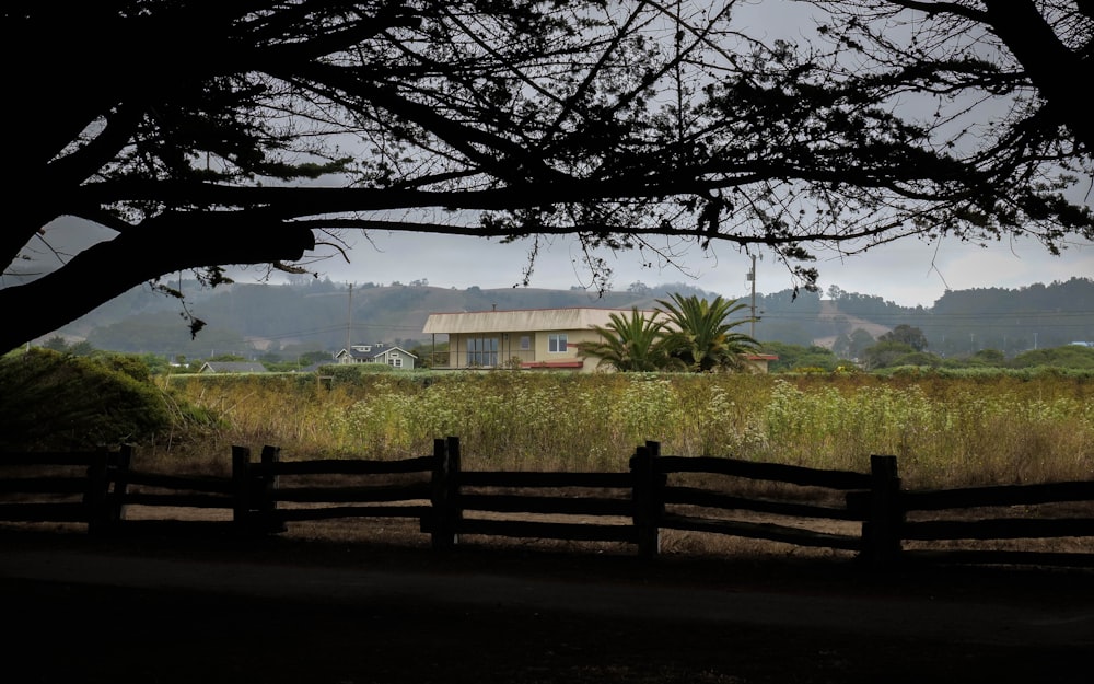 a house in the distance with a fence in front of it