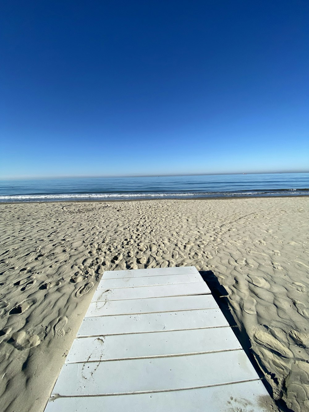 a wooden bench sitting on top of a sandy beach