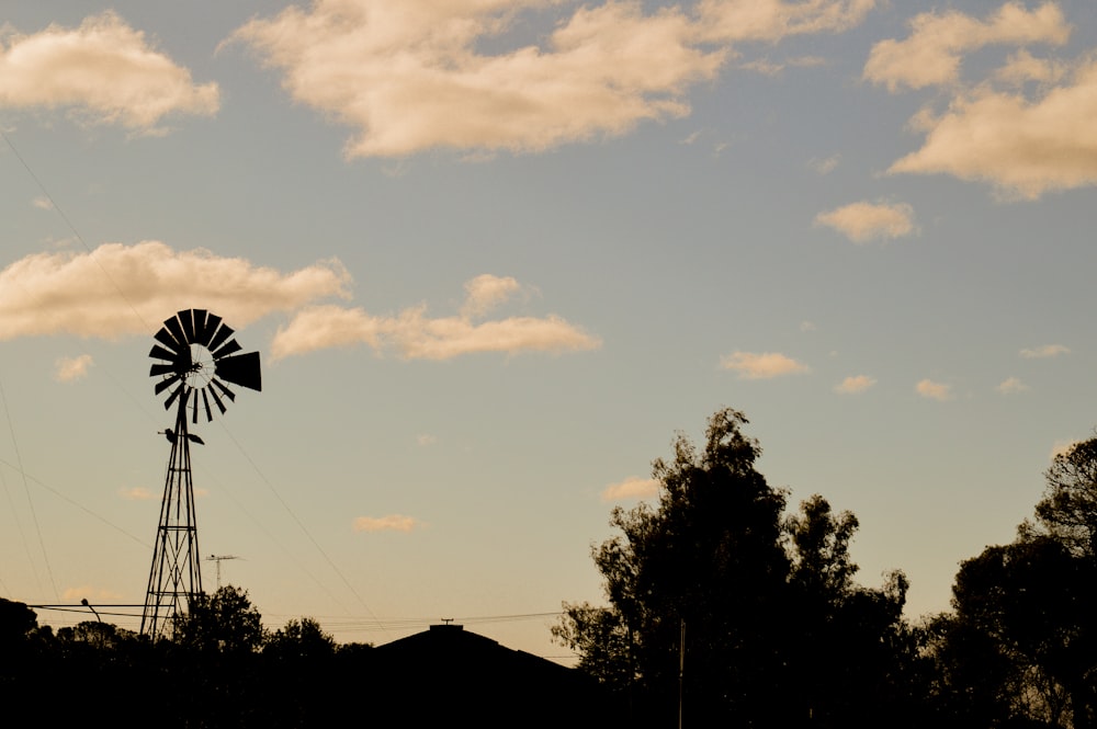 a windmill is silhouetted against a cloudy sky