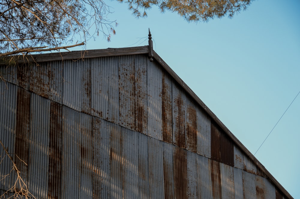 a rusted metal building with a tree in the foreground
