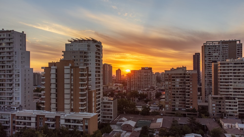 the sun is setting over a city with tall buildings