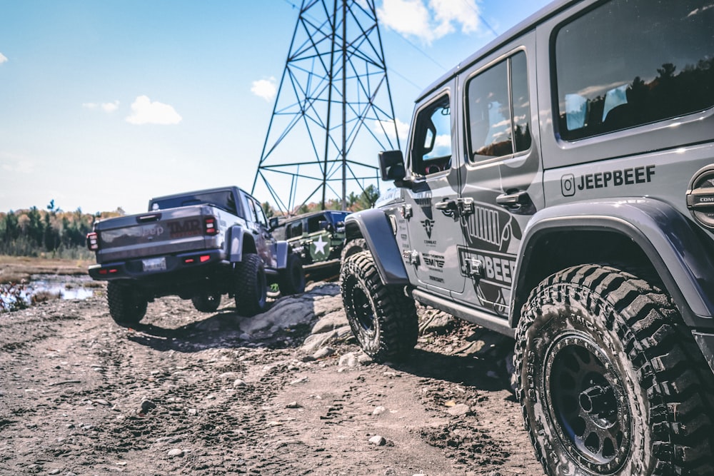 two jeeps parked in the mud near a power line