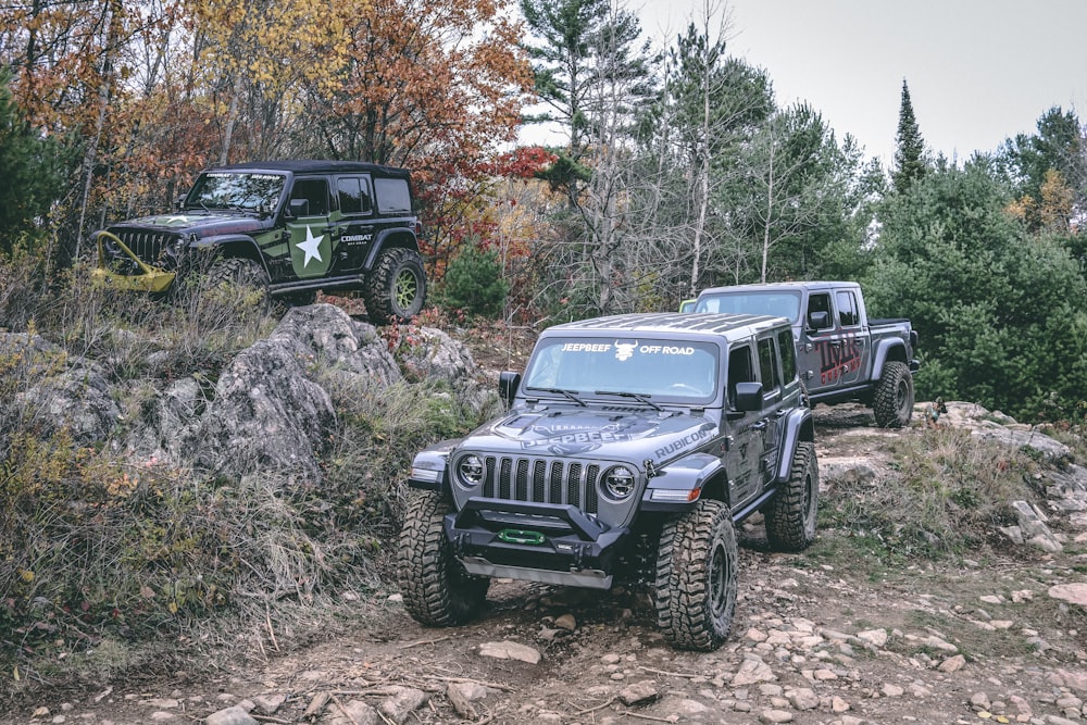 two jeeps driving on a rocky trail in the woods