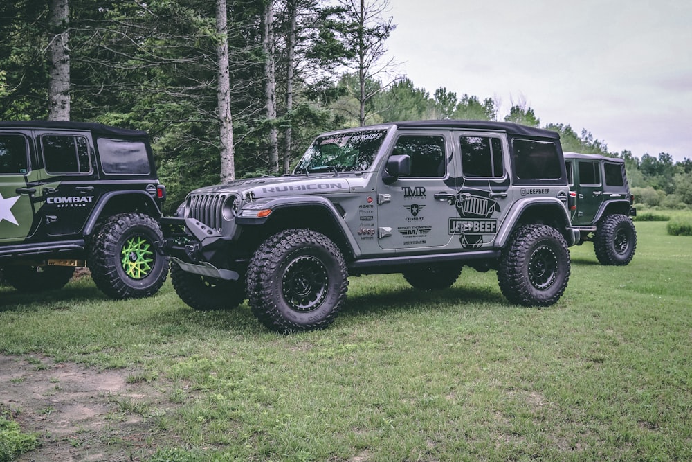 two jeeps are parked in a grassy field