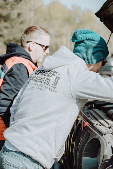 a couple of men standing next to a parked car