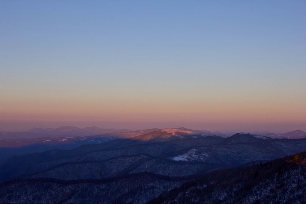 a view of the mountains at sunset from the top of a mountain