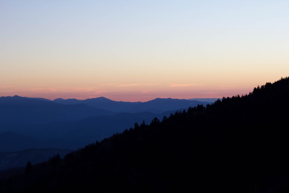 a silhouette of a mountain with a sunset in the background