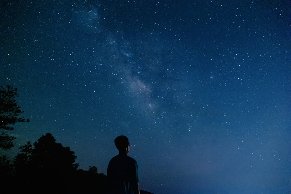 a man looking up at the stars in the night sky