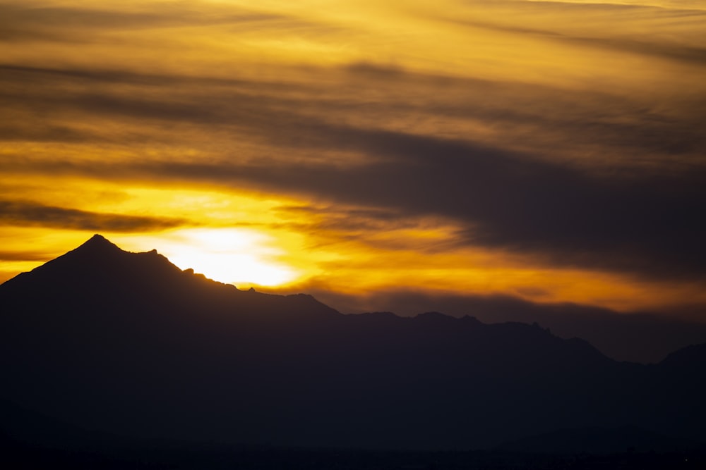 the sun is setting behind a mountain range