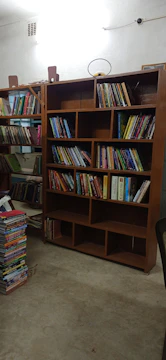 A handyman assembling a wooden bookshelf in a bright, cozy room.
