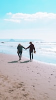 Two people walking hand in hand along a scenic beach.