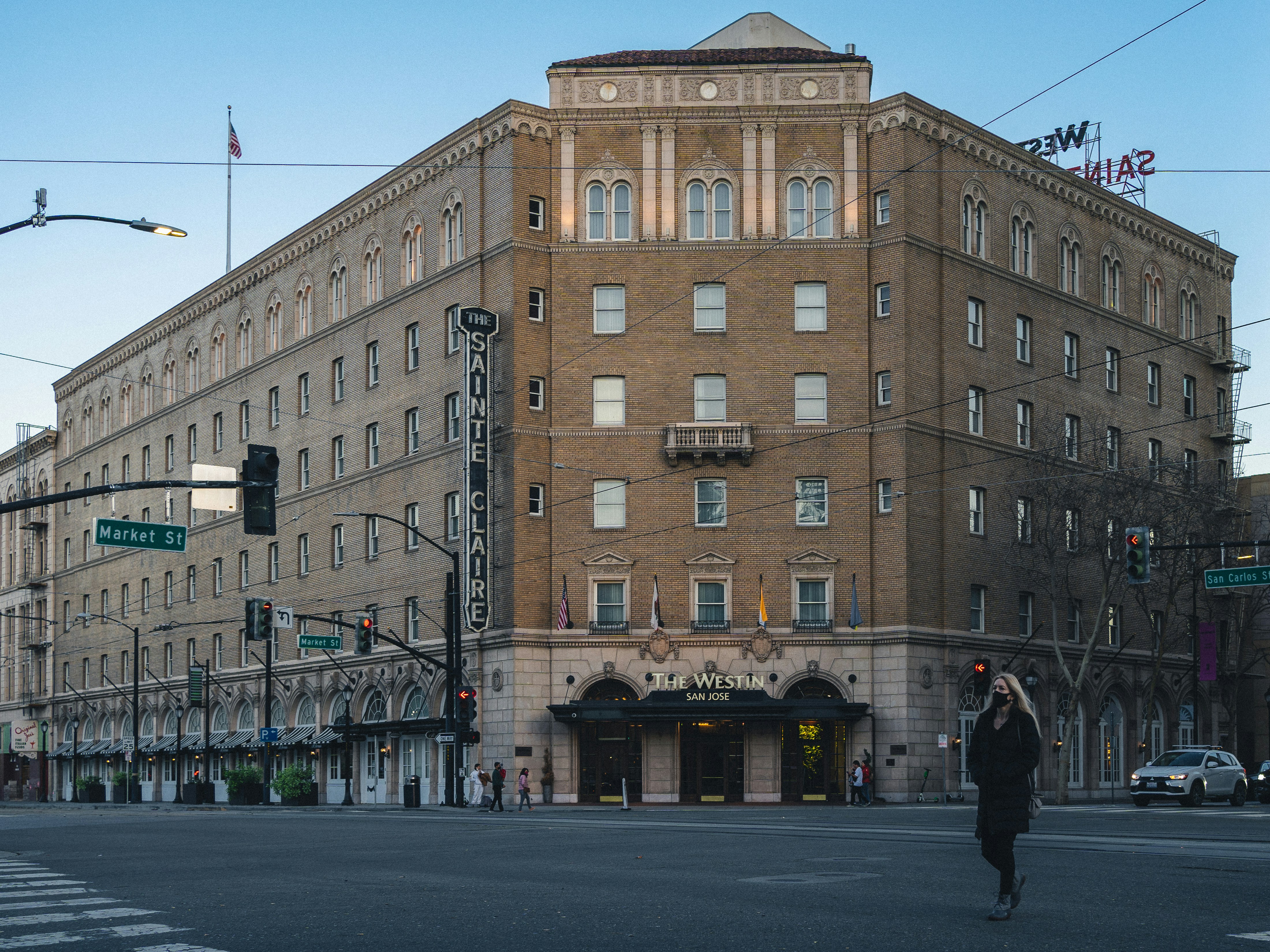 a man walking across a street in front of a tall building