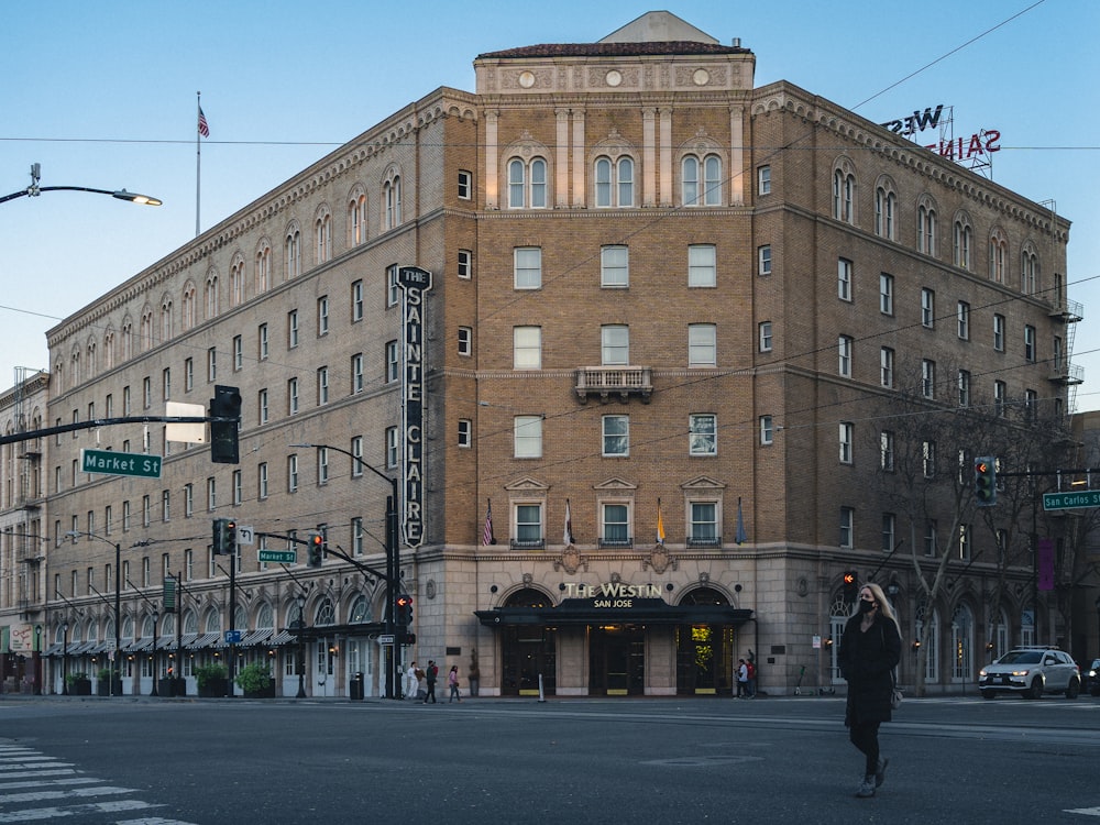 a man walking across a street in front of a tall building