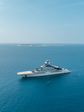 A luxury yacht sailing on clear turquoise Caribbean waters under a bright sky.