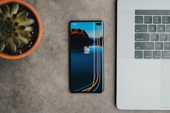 a cell phone sitting next to a laptop on a table