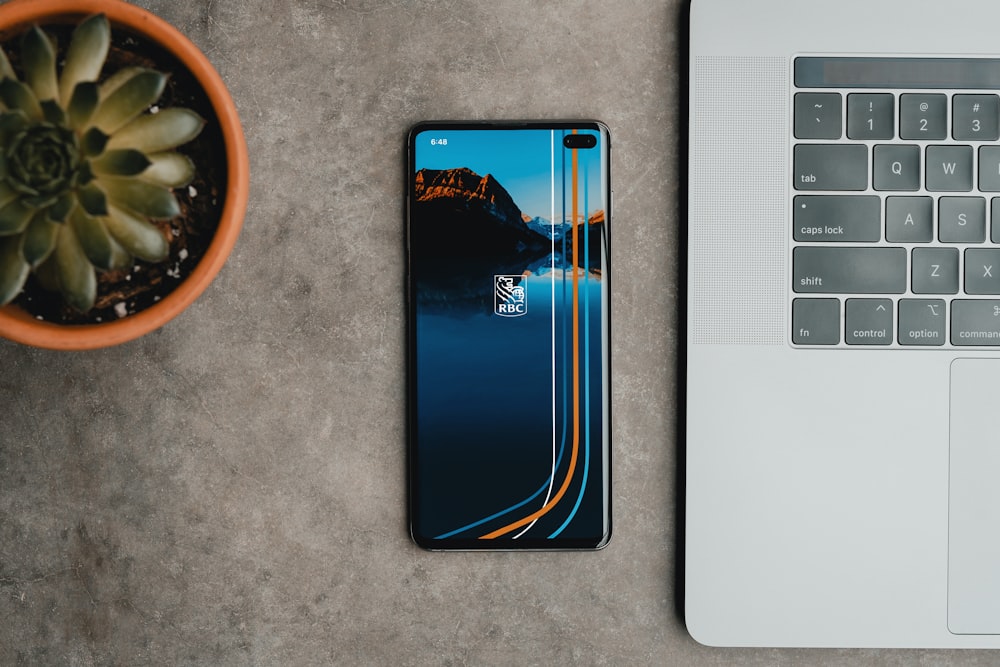 a cell phone sitting next to a laptop on a table