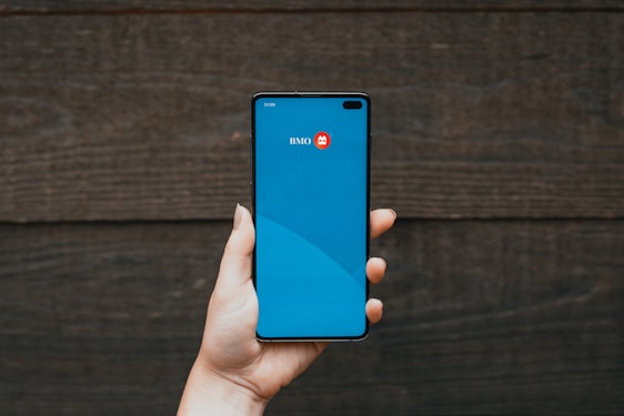Hand holding a smartphone with a banking app on the screen.