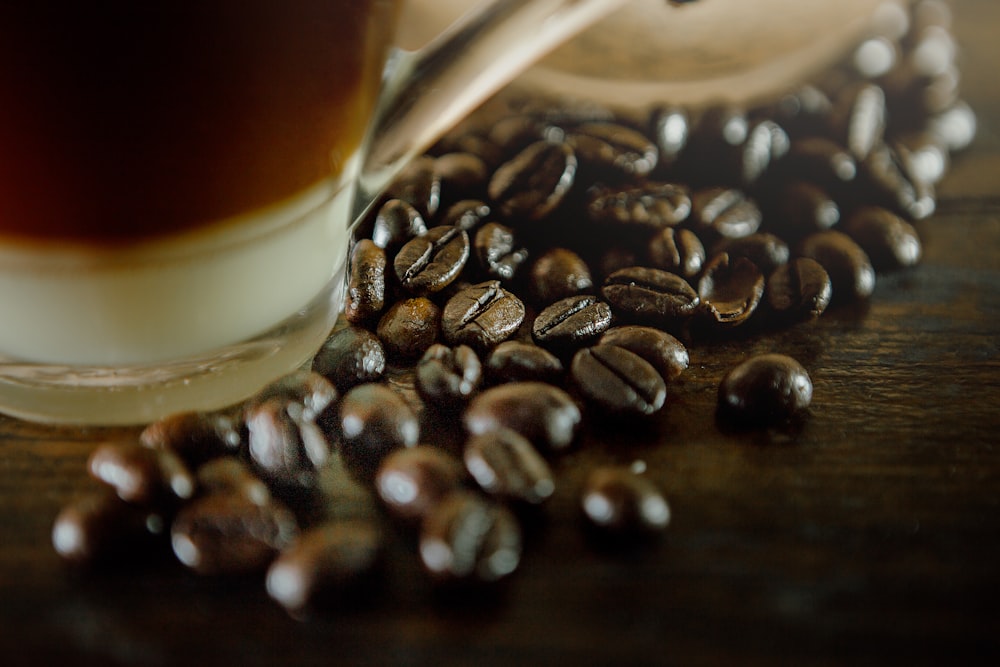 a cup of coffee sitting next to a pile of coffee beans