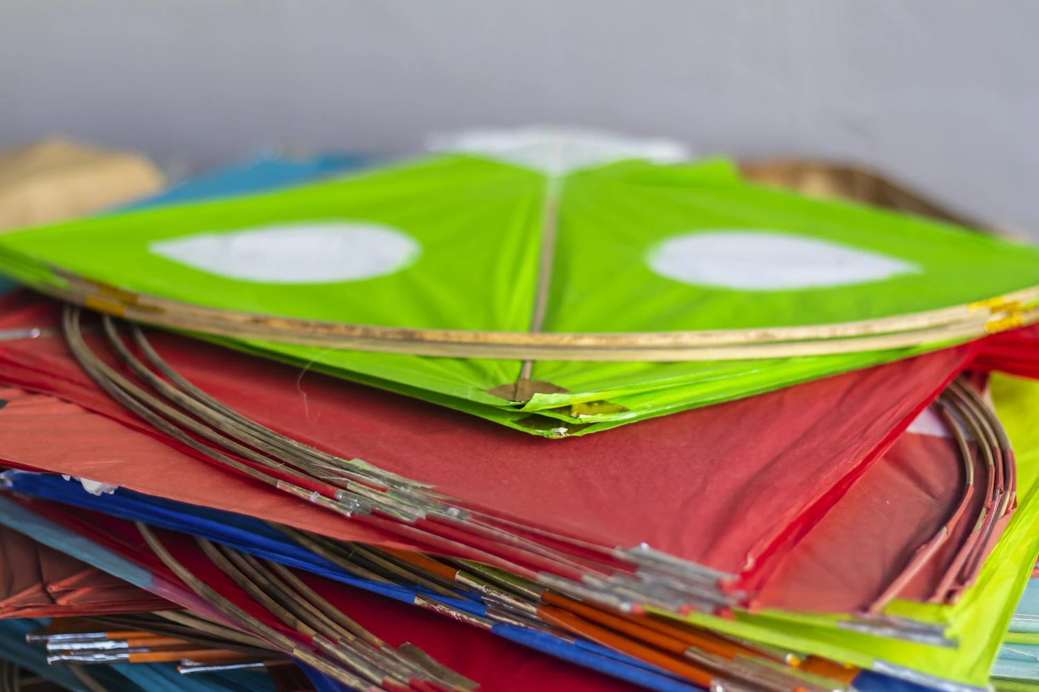 A stack of finished red, green and white kites piled on the bench