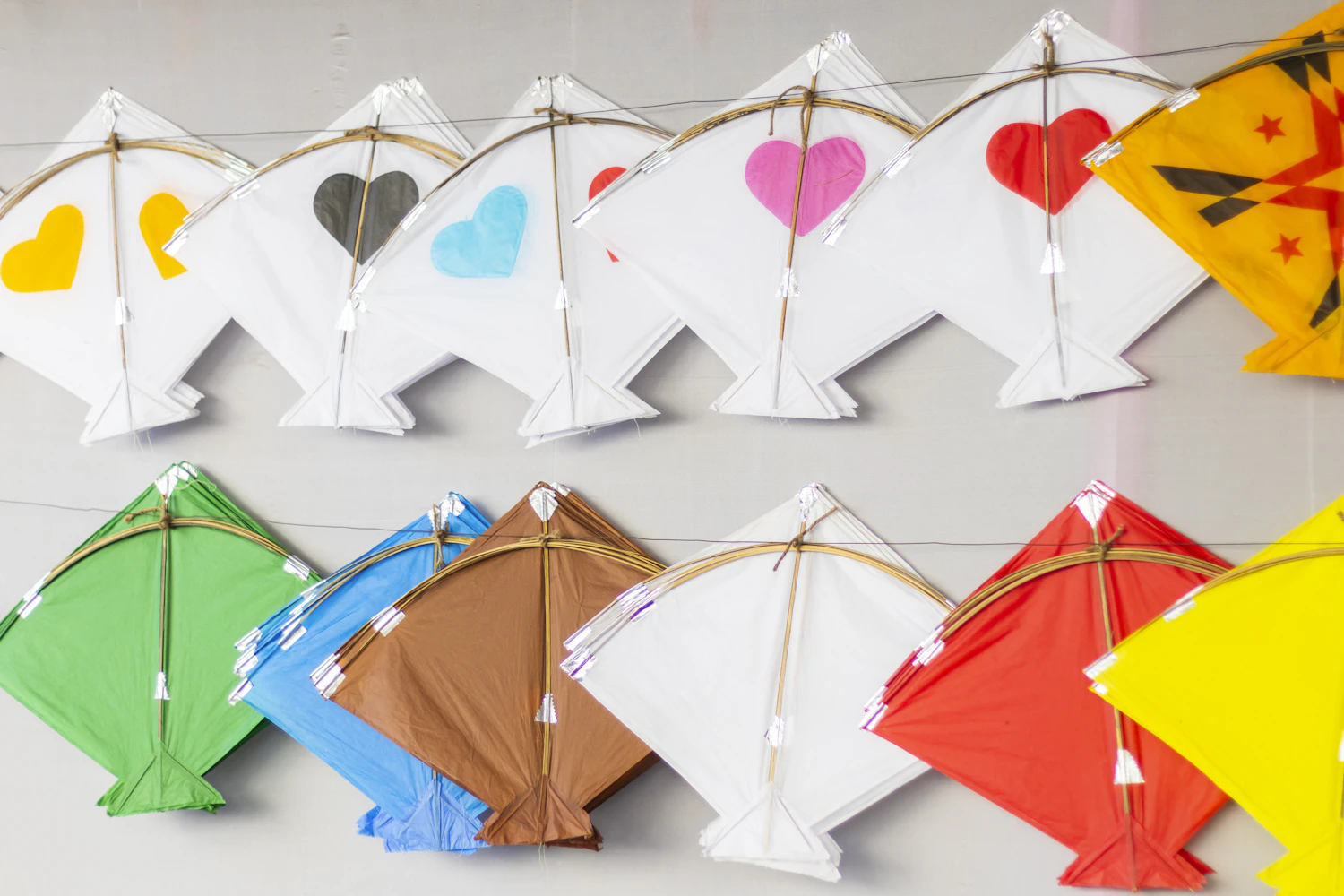 Rows of painted paper kites with tassels hanging on the drying wall