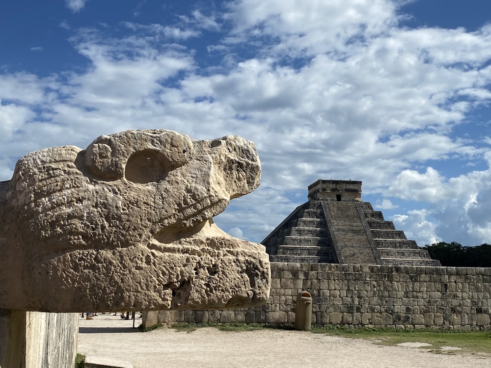 a stone sculpture of a head in front of a pyramid