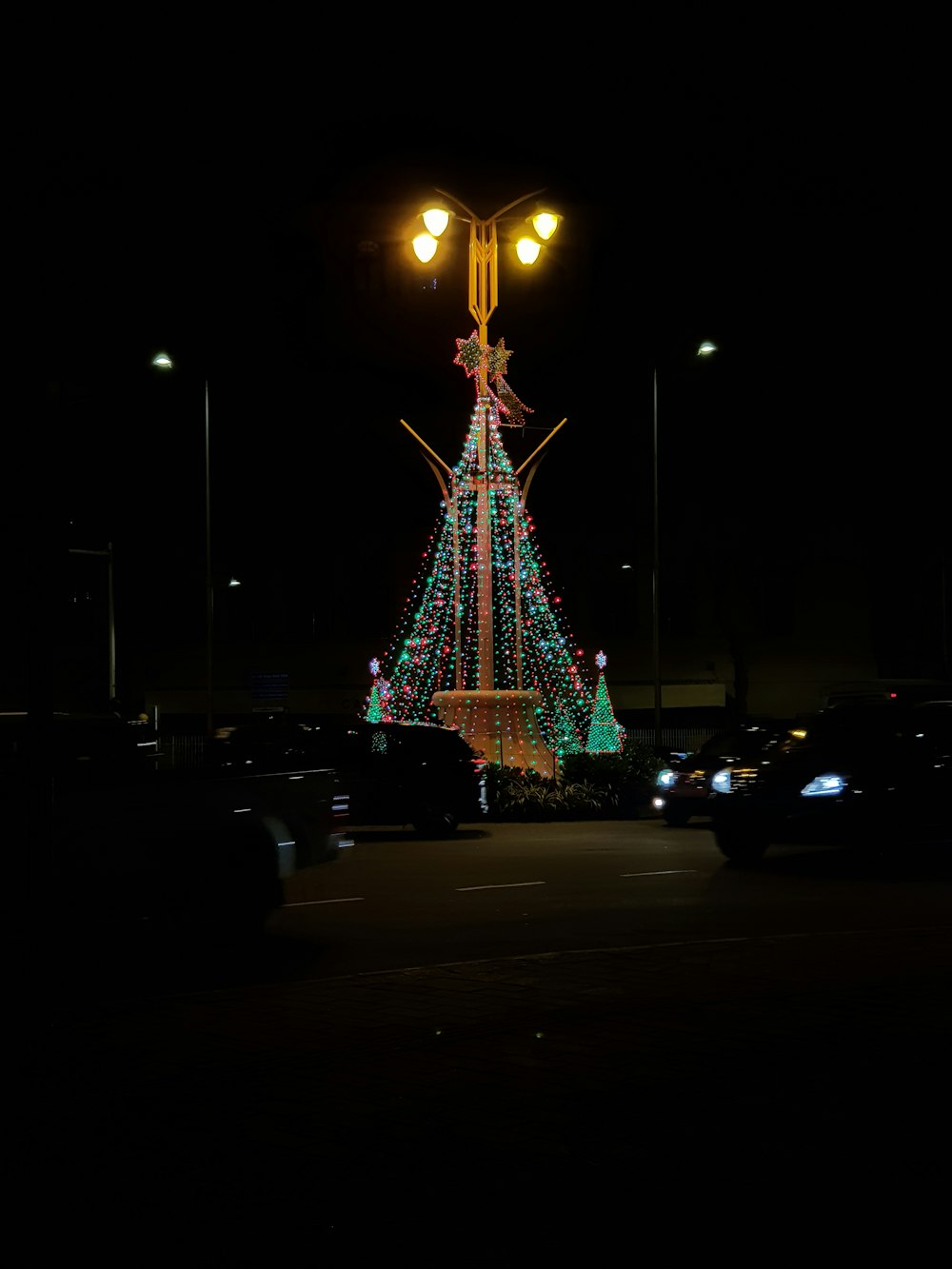 a lighted christmas tree in the middle of a parking lot