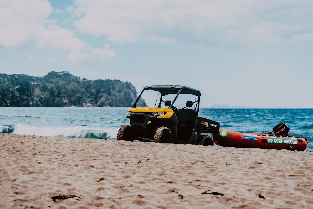 a small vehicle parked on a beach next to a body of water