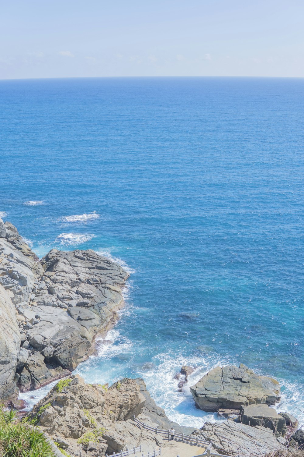 a couple of people sitting on top of a cliff next to the ocean