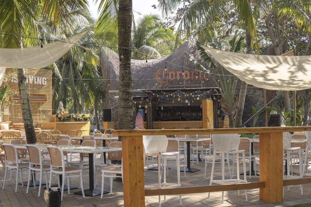 a wooden deck with tables and chairs under a canopy,