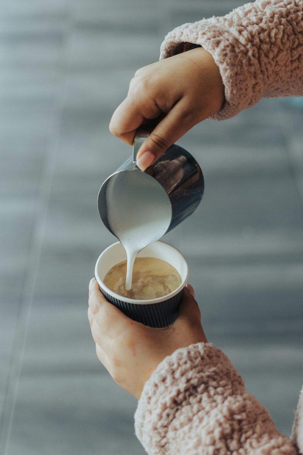 a person pouring milk into a cup of coffee