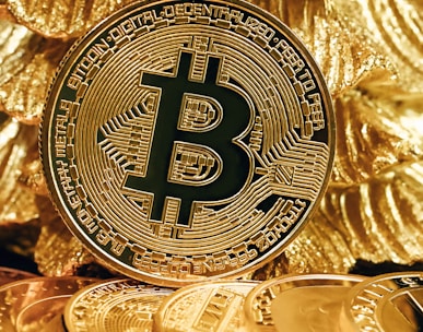 a bitcoin sitting on top of a pile of gold coins