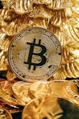 a bitcoin sitting on top of a pile of gold coins